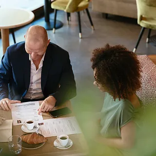 Three people around a table, drinking coffee and looking at a CV