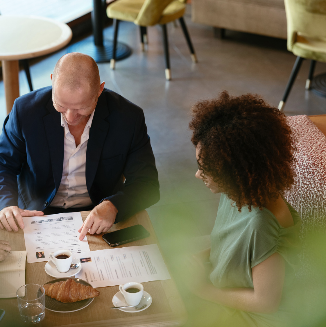 Three people around a table, drinking coffee and looking at a CV